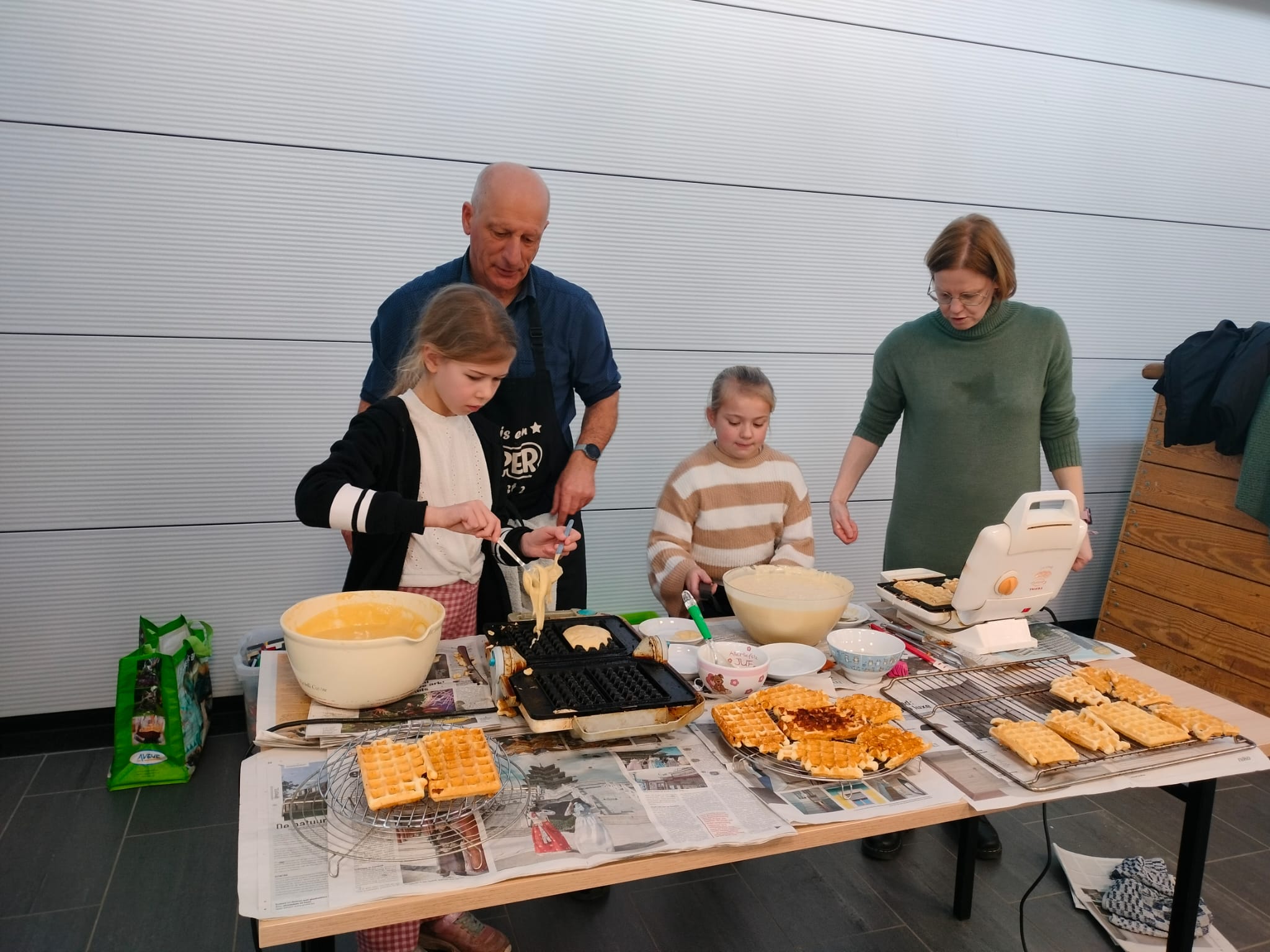 Kinderen en leerkrachten bakken wafels. 